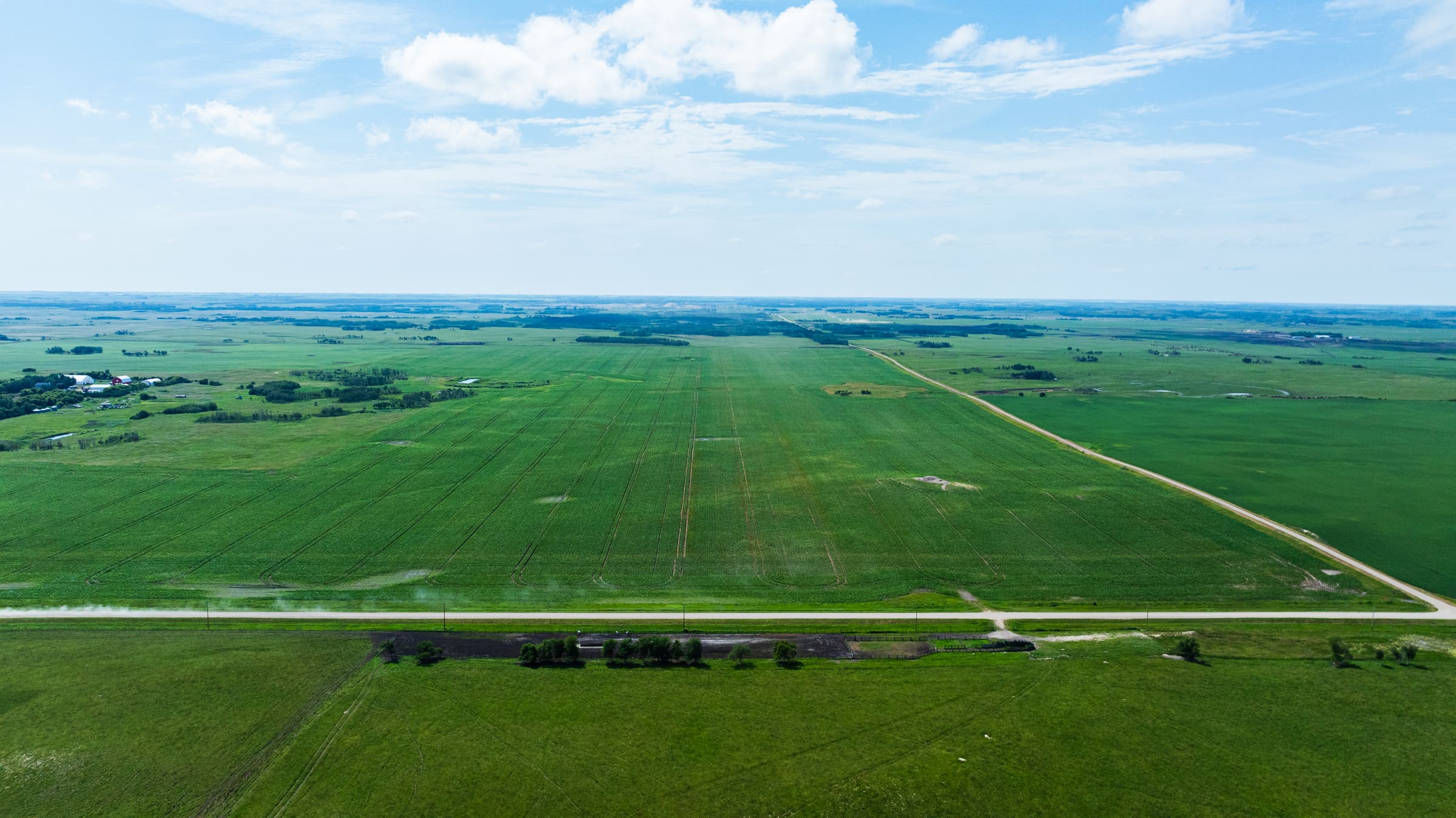 Aerial sweep of Lazy T Ranch crops and prairie roads stretching to the horizon